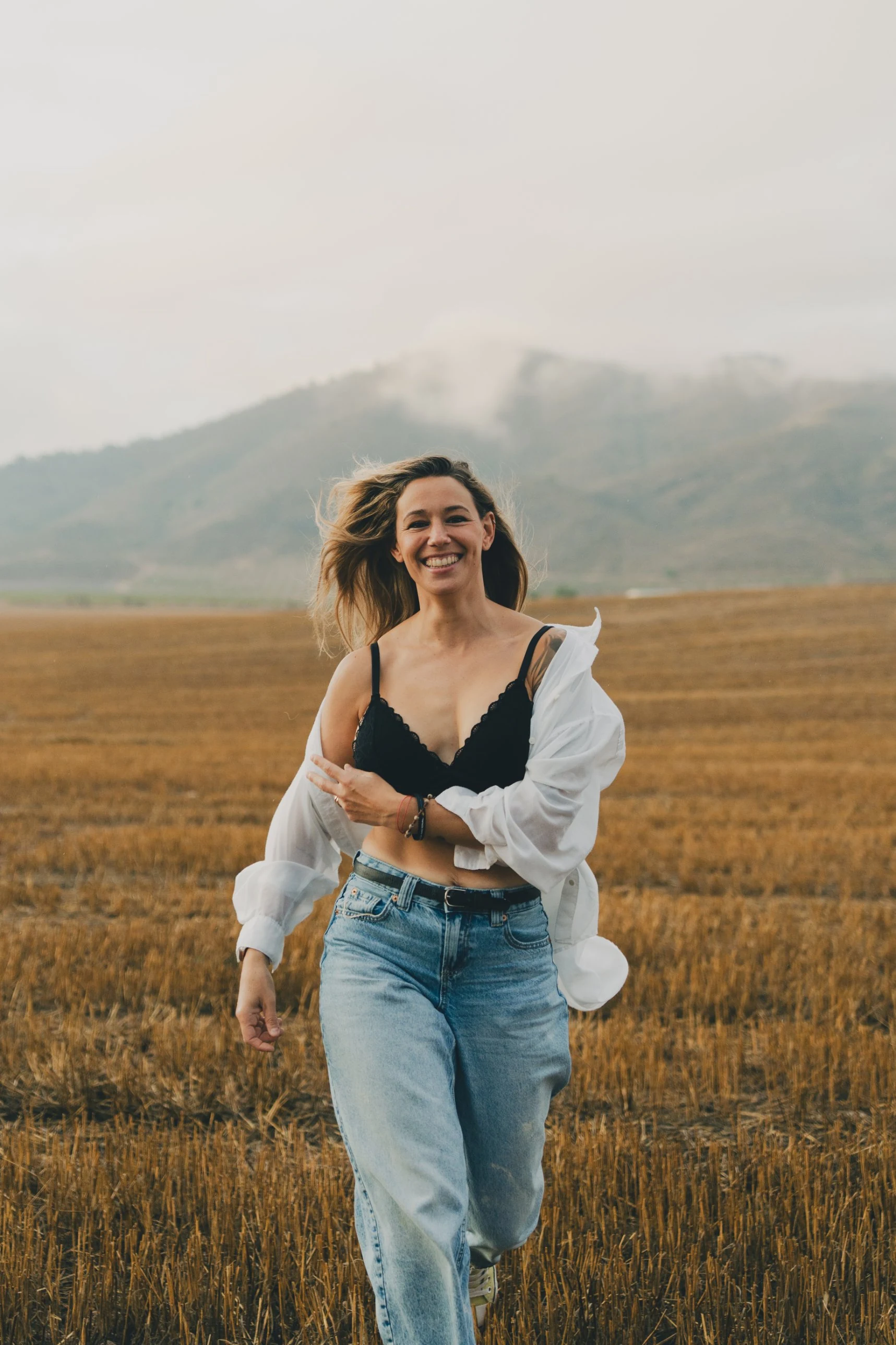 Ella corriendo por el rastrojo bajo el cielo encapotado